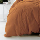 alt="A cosy bed with an orange quilt cover and a white nightstand. Elevate your bedroom with this stylish and comfortable quilt cover set.