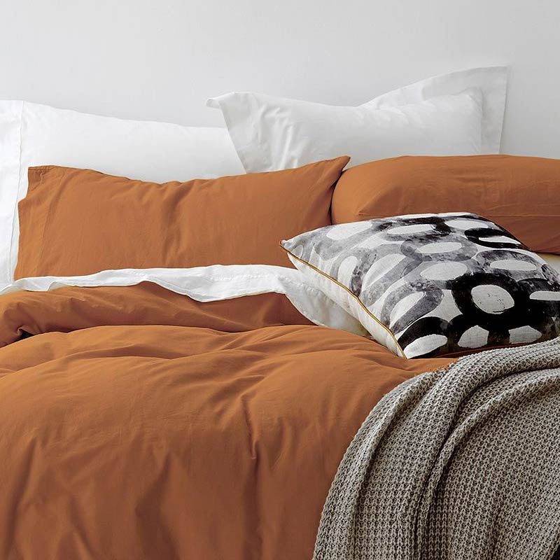 alt="A cosy bed with an orange quilt cover and pillows, adorned with the Vintage Washed Cotton Blush Quilt Cover Set for a stylish and comfortable bedroom."