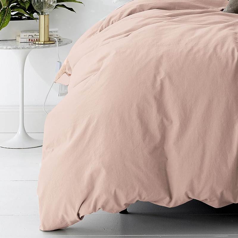alt="A cosy bed with a pink quilt cover and a white nightstand. Elevate your bedroom with this stylish and comfortable quilt cover set.