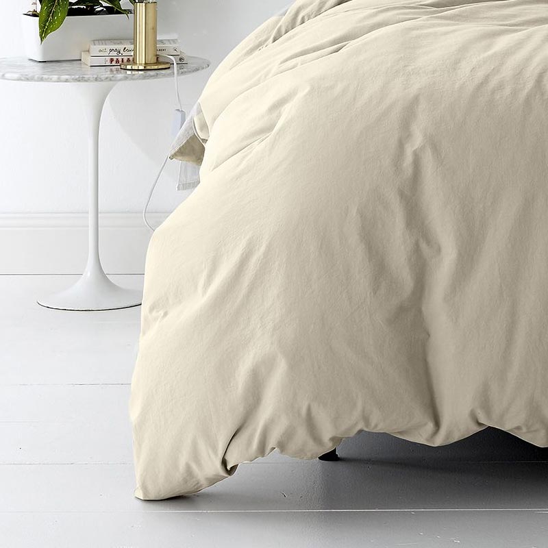 alt="A cosy bed with a shade of stone quilt cover and a white nightstand. Elevate your bedroom with this stylish and comfortable quilt cover set.